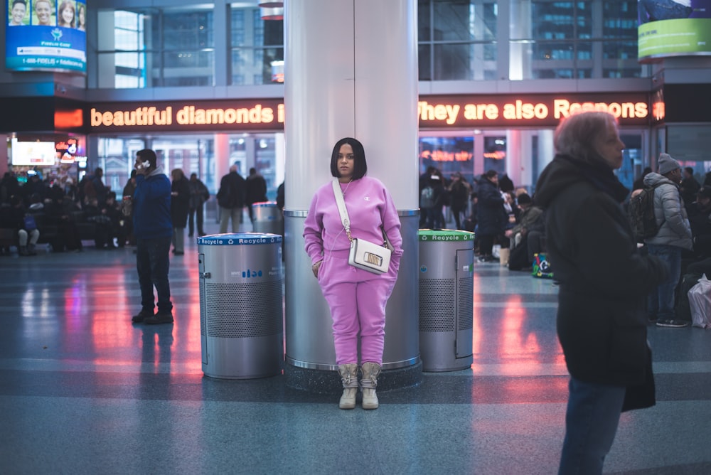 standing woman in front of white concrete post inside building