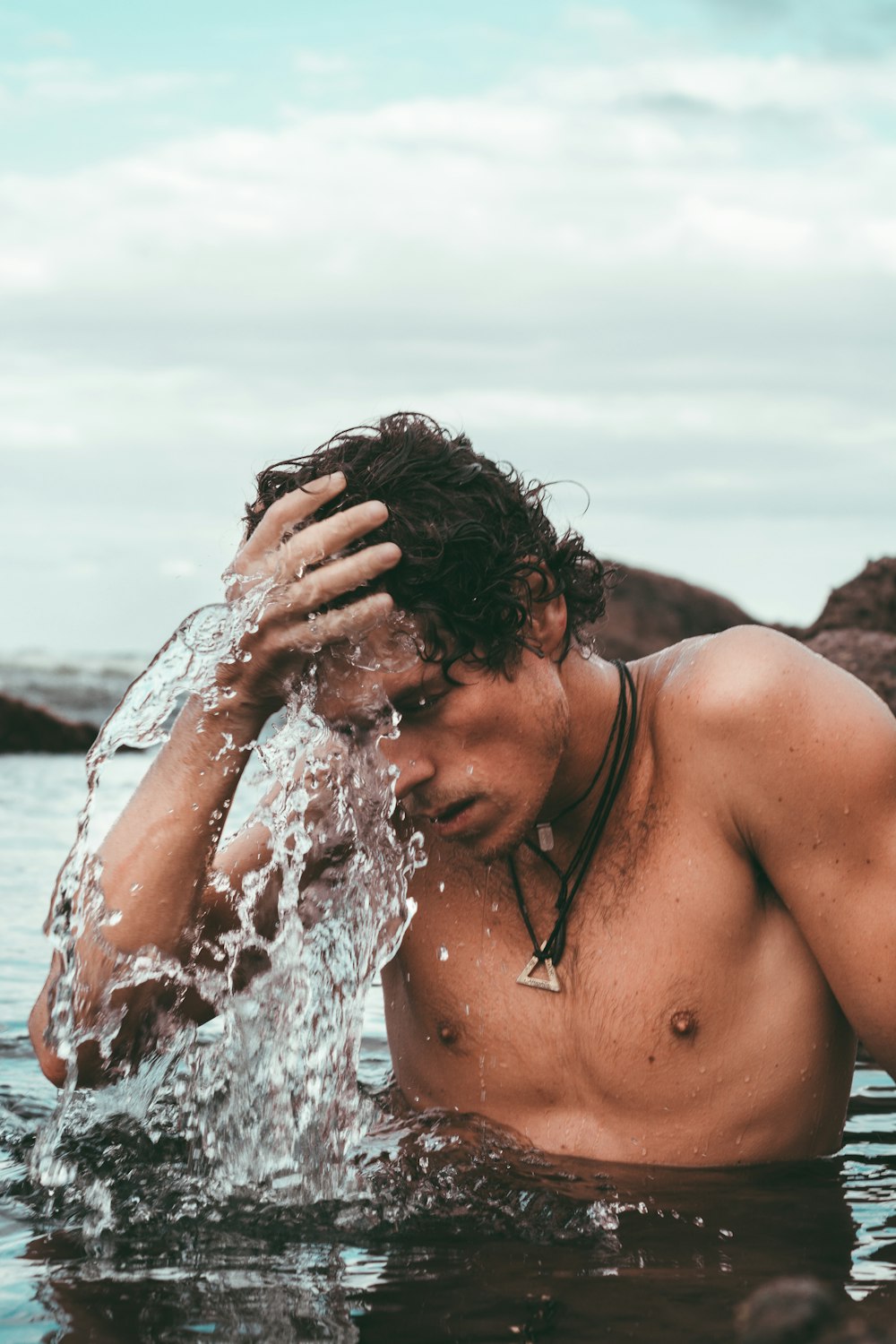 topless man bathing on lake