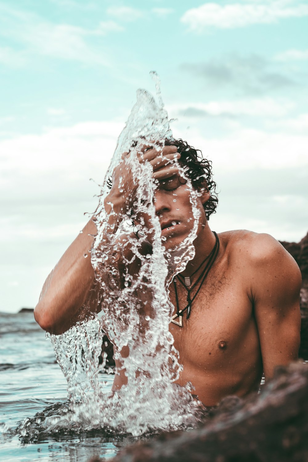 uomo in topless che fa il bagno in riva al mare