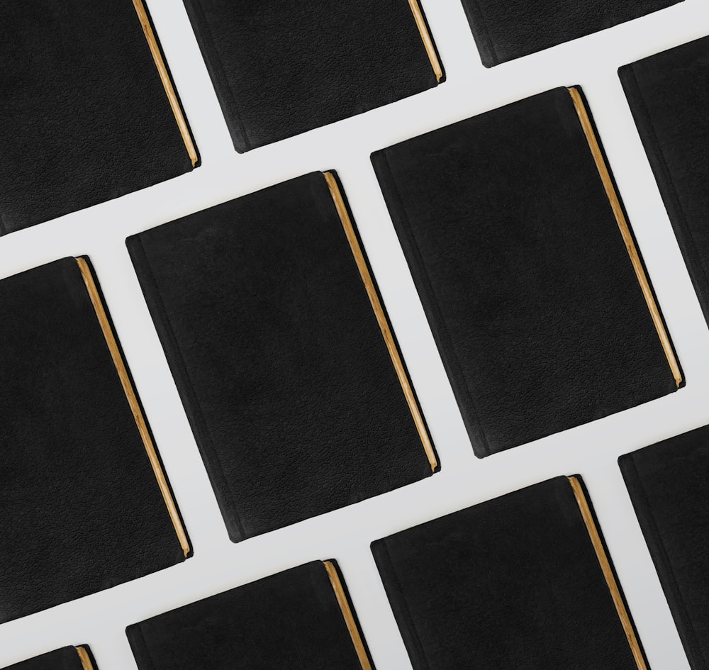 a row of black and gold books sitting on top of a white table