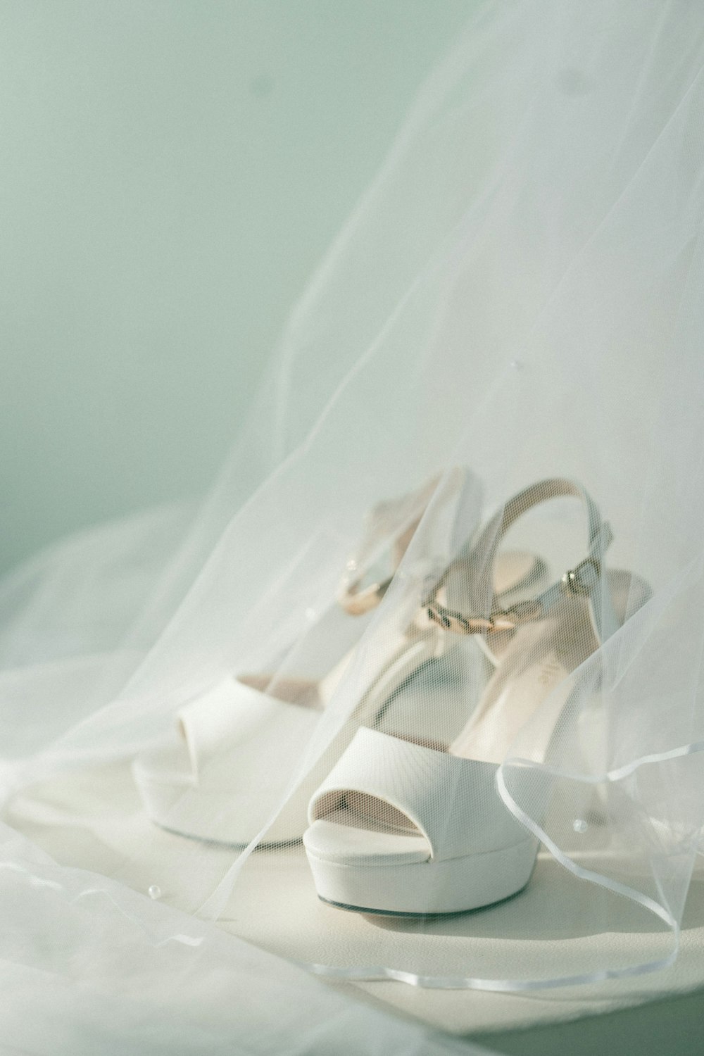 Sandalias blancas de tacón alto destalonadas con punta abierta cubiertas con velo blanco