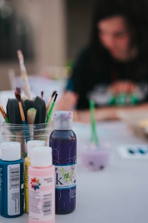 four color bottles near paint brushes
