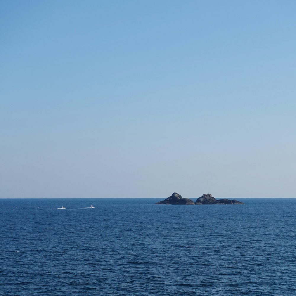 two boats on water near islet during daytime