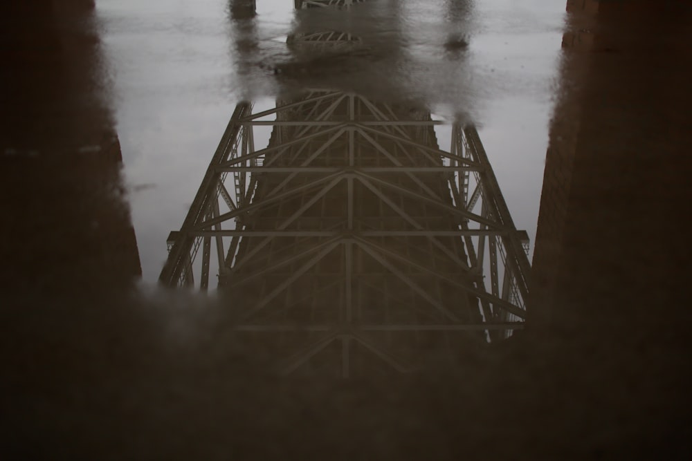 close-up photo of puddle with reflection of bridge