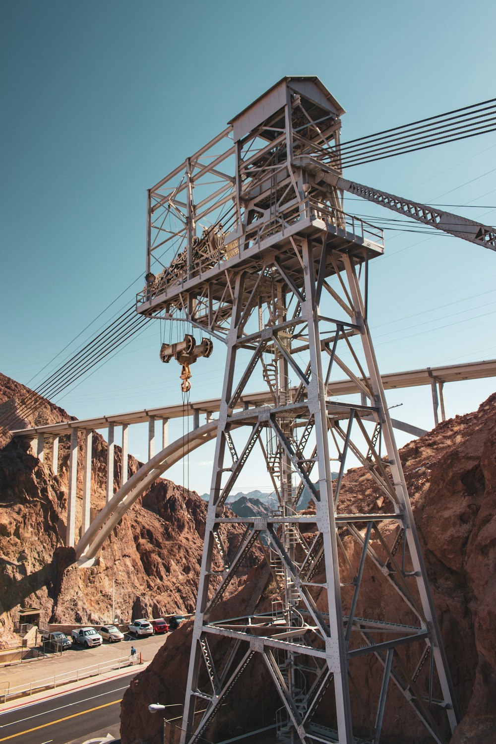 grauer Metallturm in der Nähe der Brücke über der Straße während des Tages