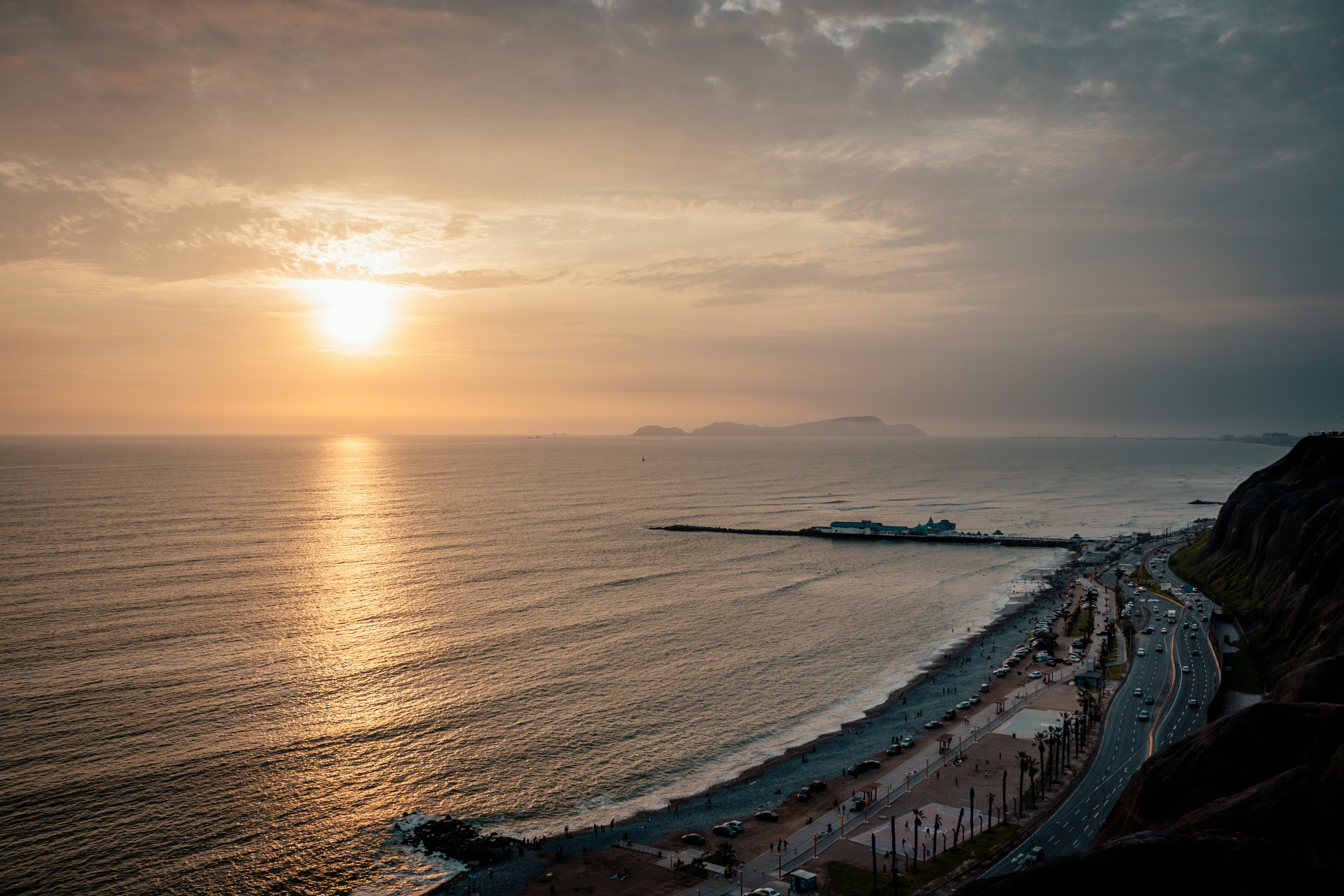 aerial photography of asphalt road beside body of water during golden hour