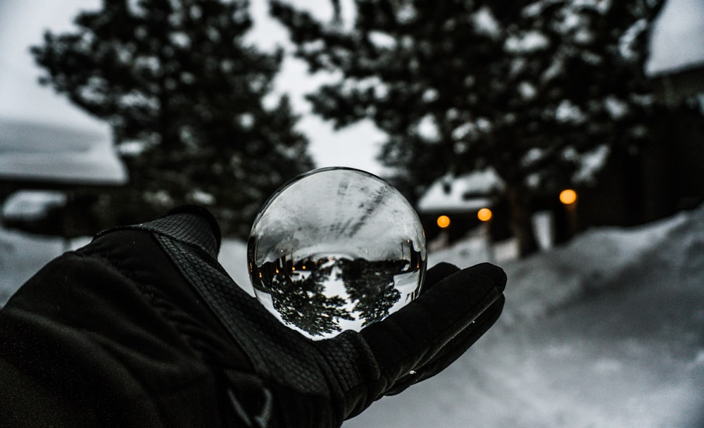 personne tenant une boule de verre transparent