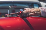 Hands carefully applying wax to a classic car’s gleaming hood.