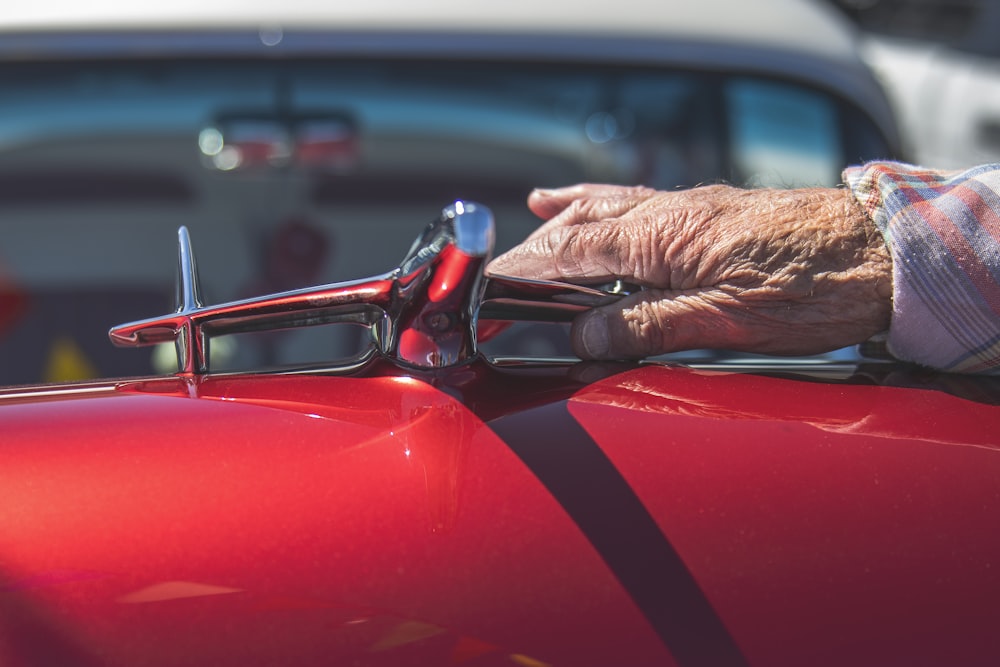 person touching chrome-colored emblem