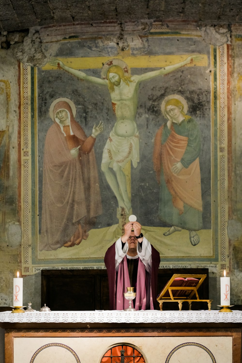 priest raising a white bread on stage