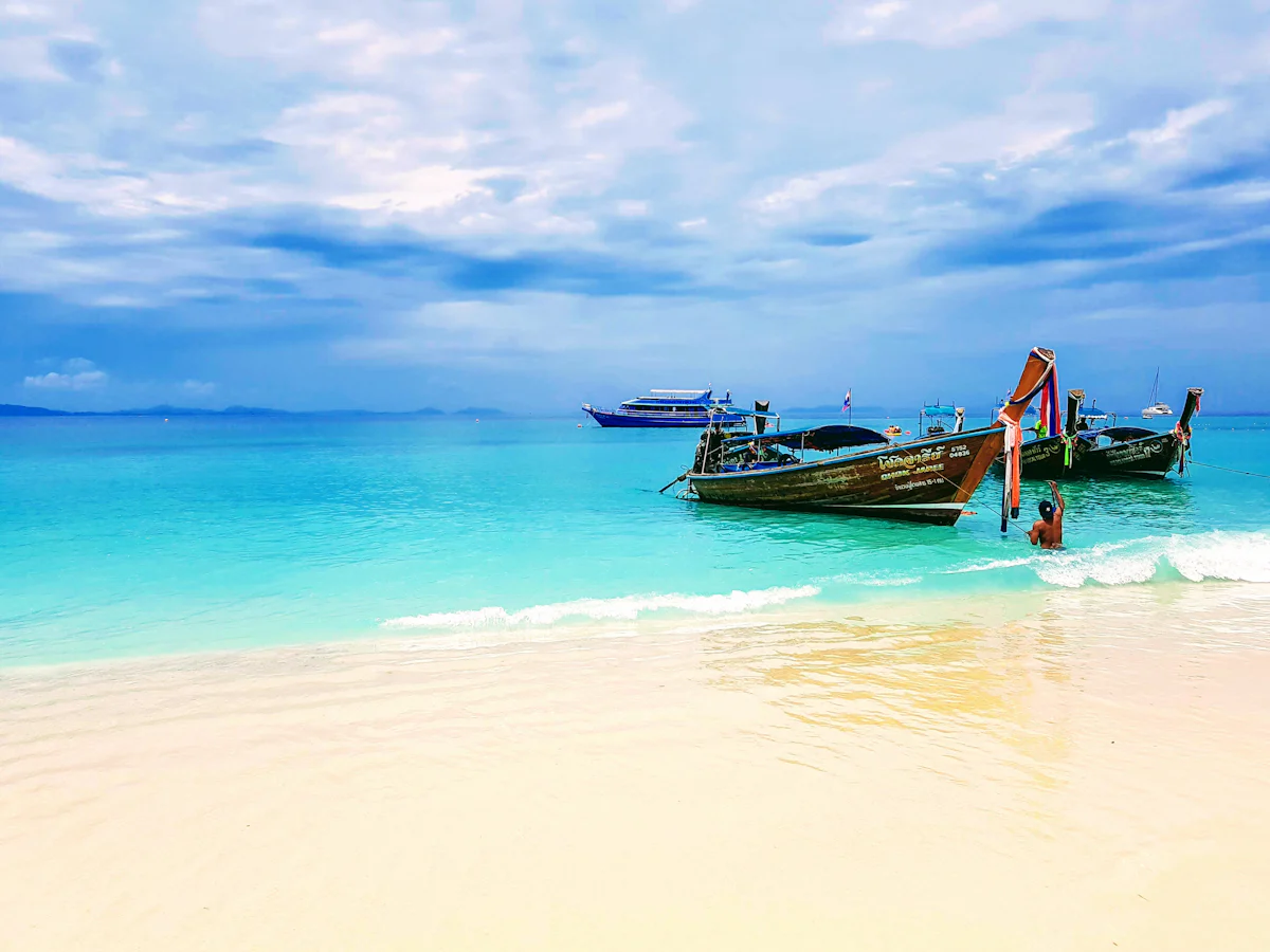 เรือหางยาวกับหน้าผาหินปูนและทะเลใสฝั่งอันดามัน