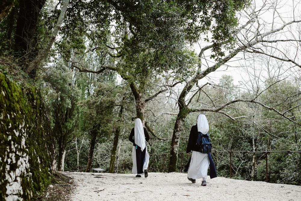 two woman walking near trees during daytime