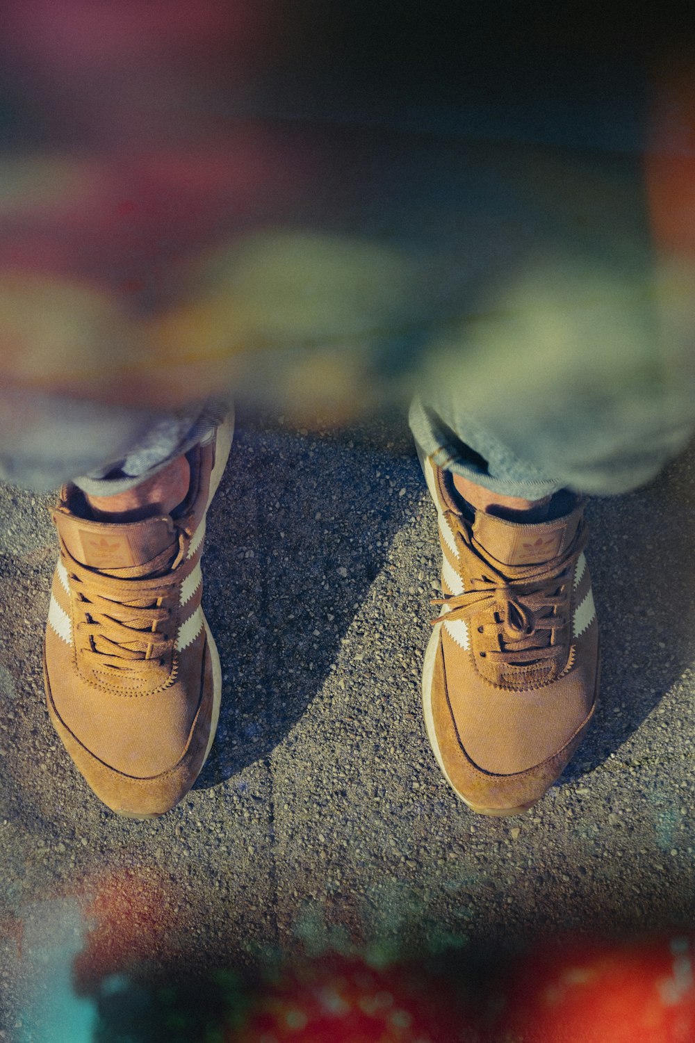 person wearing pair of brown adidas shoes on gray concrete ground