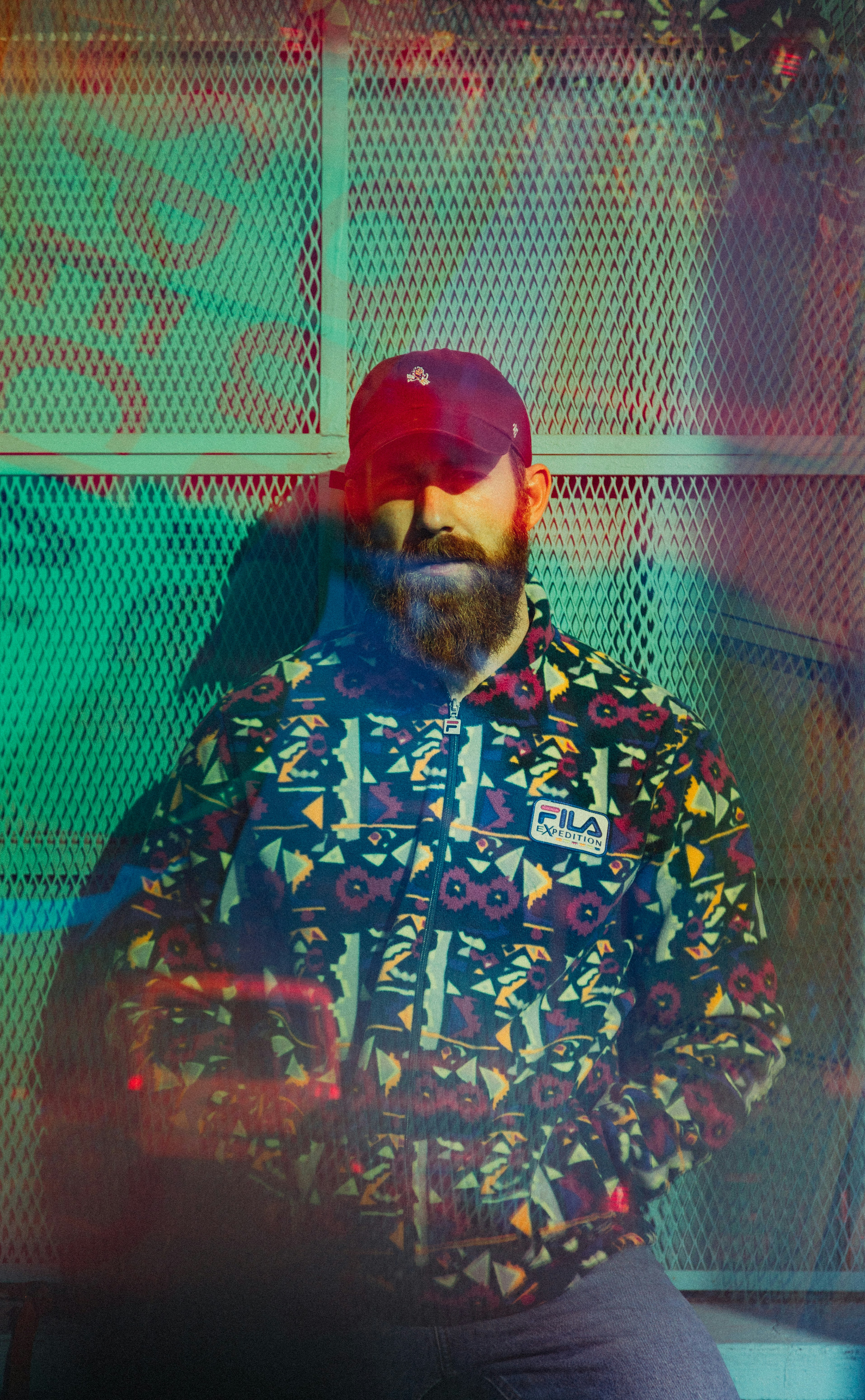 man wearing black fitted cap and multicolored FILA zip jacket during daytime