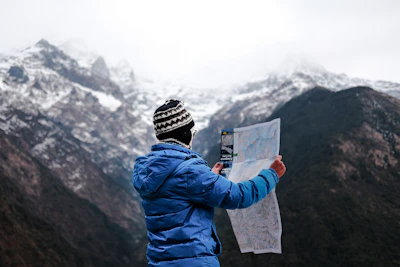 A traveler holding a map with a scenic mountain backdrop.