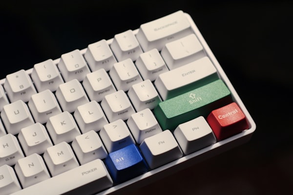 A mechanical keyboard with all-white keys except for Alt (blue), Control (red) and Shift (green)