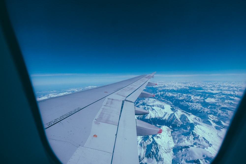 airplane window view of wing and glacier mountains