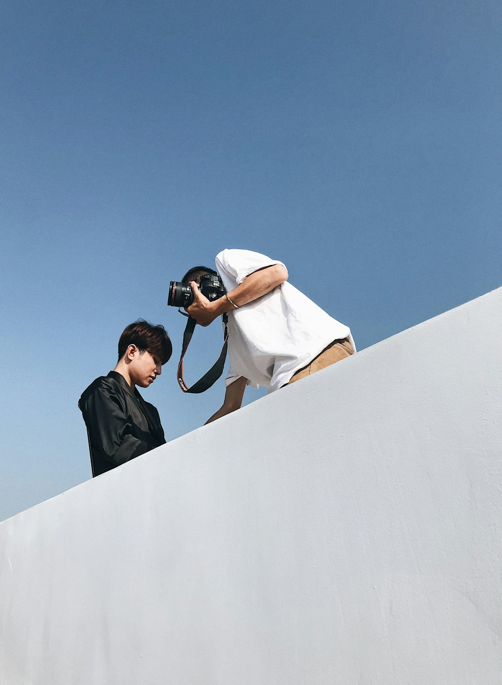 selective focus photography of man wearing black long-sleeved shirt and camera man holding camera during daytime