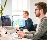 man sitting on chair wearing gray crew-neck long-sleeved shirt using Apple Magic Keyboard