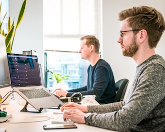 man sitting on chair wearing gray crew-neck long-sleeved shirt using Apple Magic Keyboard