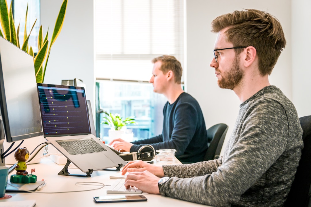 Team members in an office setting working on computers around a table, discussing how to streamline contact center operations through knowledge sharing