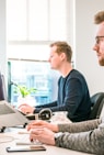 man sitting on chair wearing gray crew-neck long-sleeved shirt using Apple Magic Keyboard