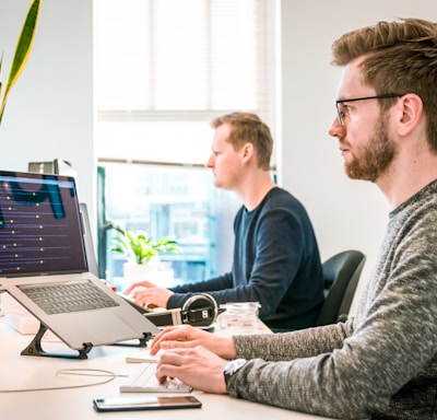 man sitting on chair wearing gray crew-neck long-sleeved shirt using Apple Magic Keyboard