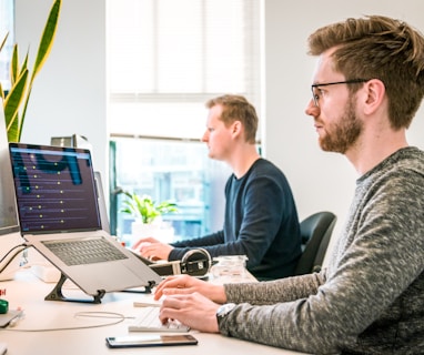 man sitting on chair wearing gray crew-neck long-sleeved shirt using Apple Magic Keyboard