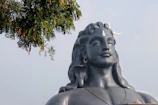 A serene statue of Lord Shiva with a glowing crescent moon atop his head amidst temple shadows.