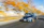 A mach1 speeding along a winding mountain road with autumn leaves blurring past.