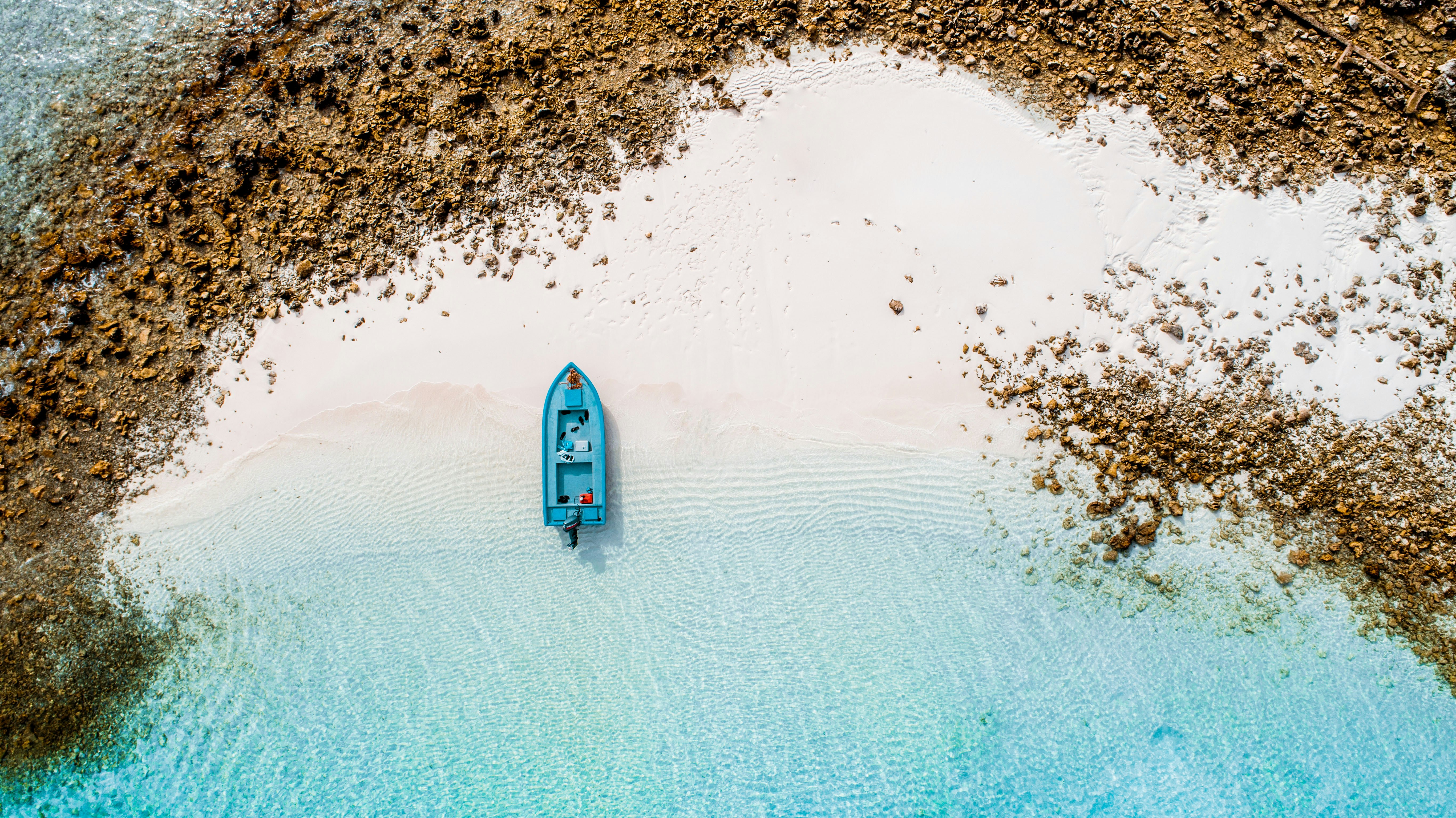 aerial photography of blue boat on seashore