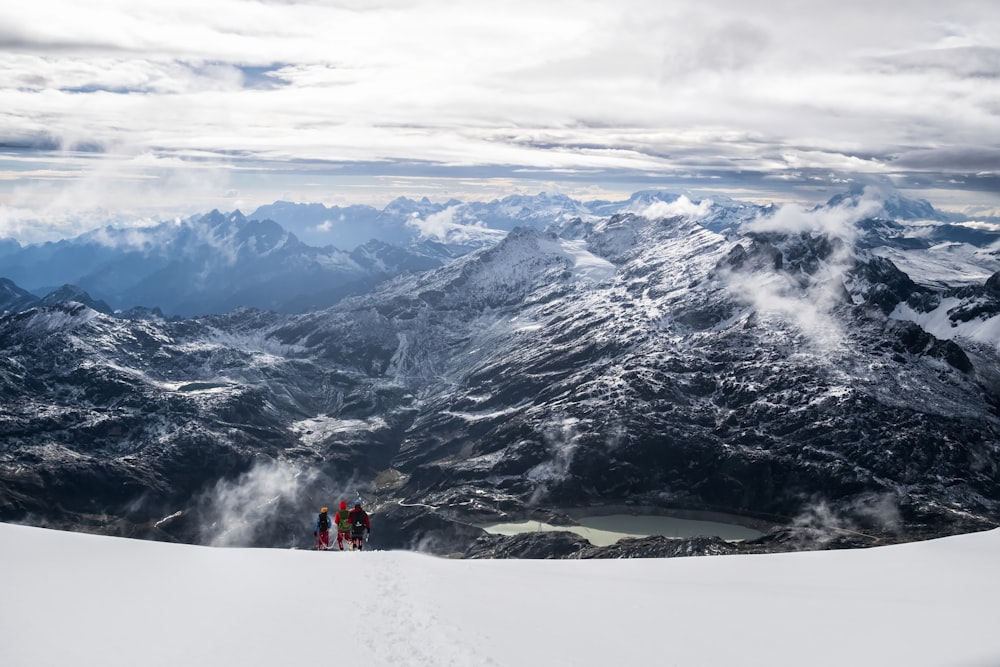 Luftaufnahme von drei Personen auf dem Gipfel eines schneebedeckten Berges bei Tag