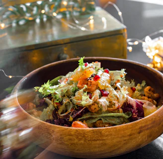 A colorful salad bowl packed with crisp greens, exotic vegetables, and juicy fruits on a rustic wooden table.