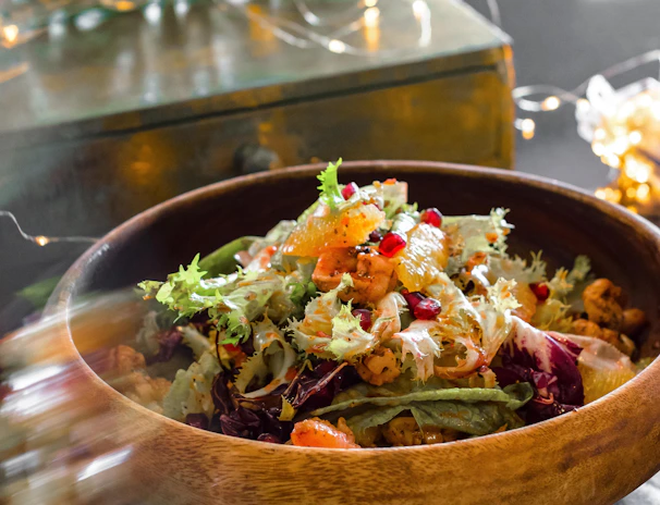 A colorful salad bowl packed with crisp greens, exotic vegetables, and juicy fruits on a rustic wooden table.