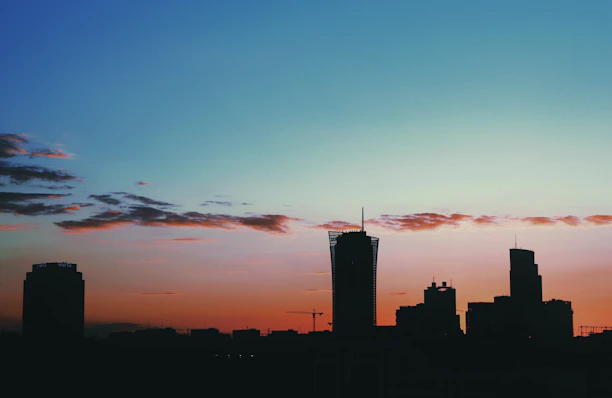 Modern architectural blueprint overlaying a city skyline at sunset.