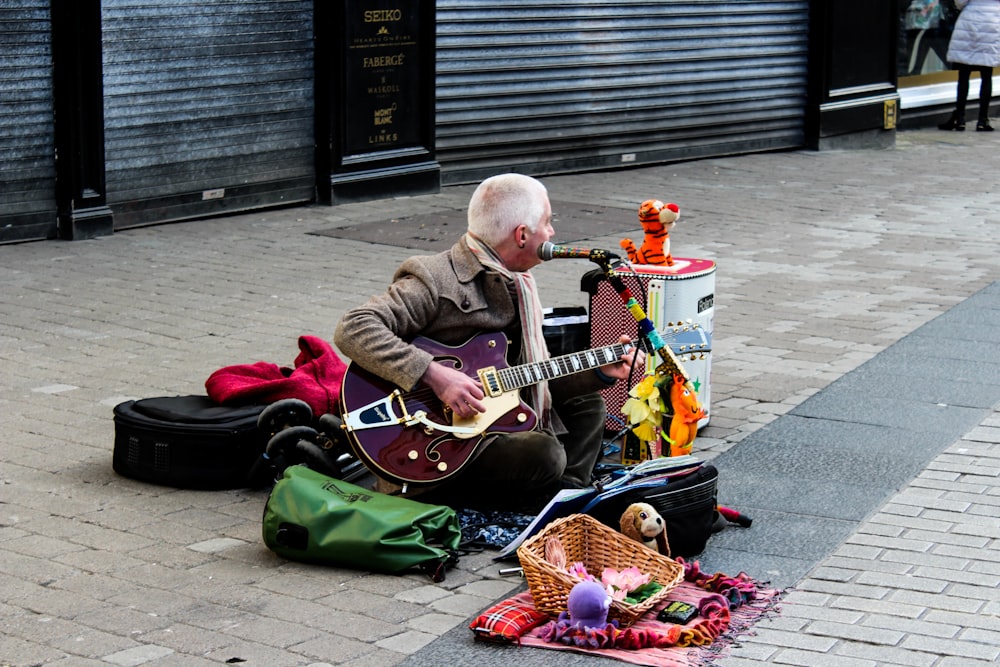 man playing maroon electric guitar on street