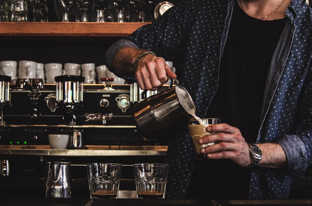 Person, die Milch auf Glas gießt