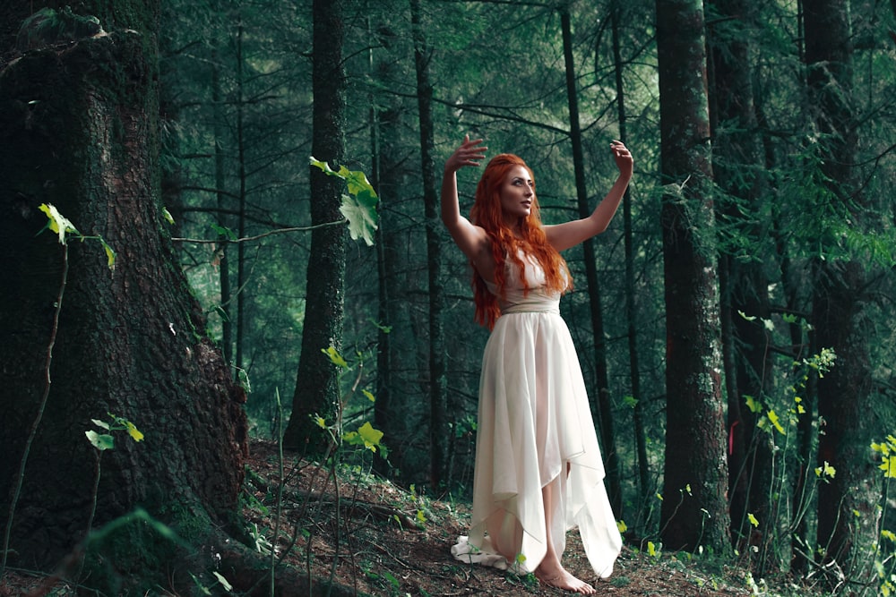 woman wearing white high-low dress in middle of woods during daytime