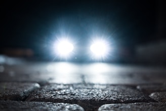 turned-on vehicle headlight on the street