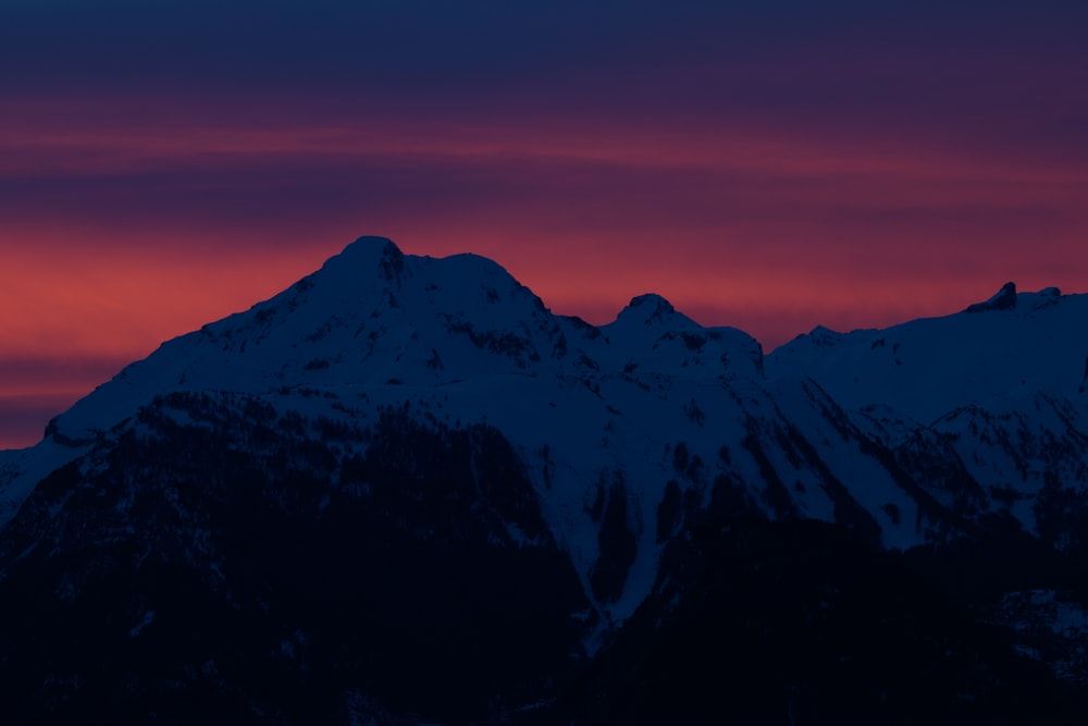 montagne au sommet de la neige sous un ciel orangé