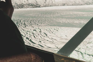 A small plane flying low over glaciers with icy blue crevasses visible from above