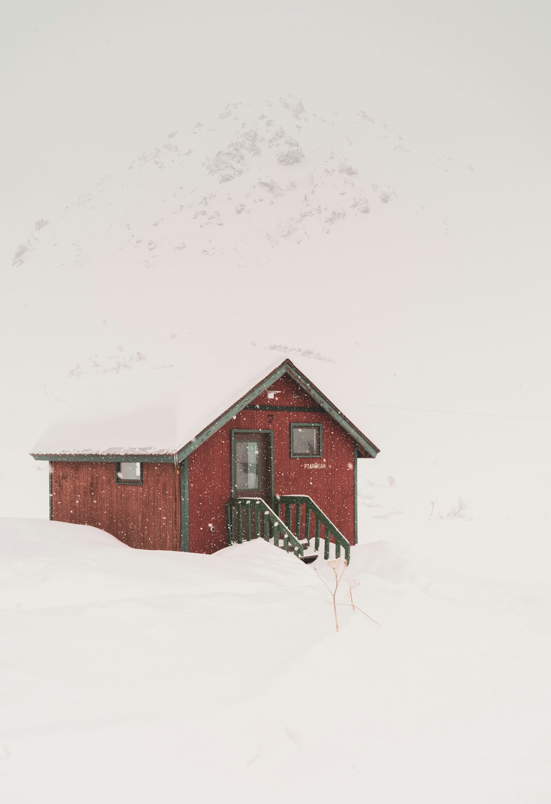 red wooden house and field covered with snow