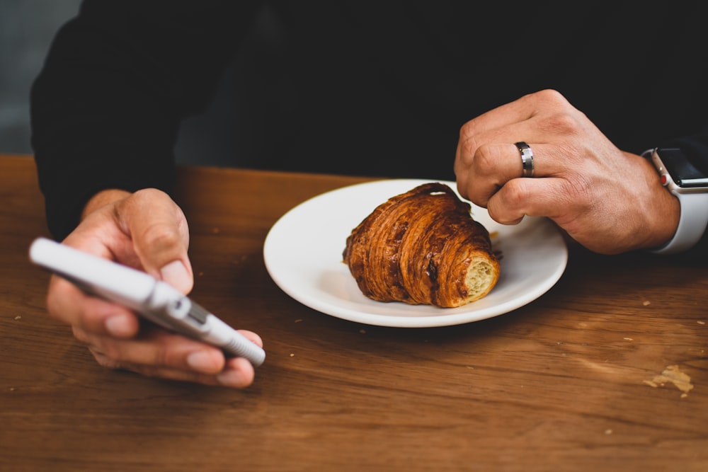 person wearing silver-colored ring holding white smartphone