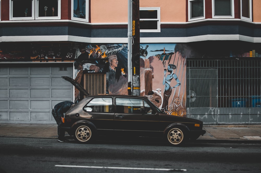 person ducking in front of car