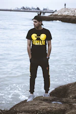 Portrait of Yassin Papito standing by the coastline, with ships in the background.