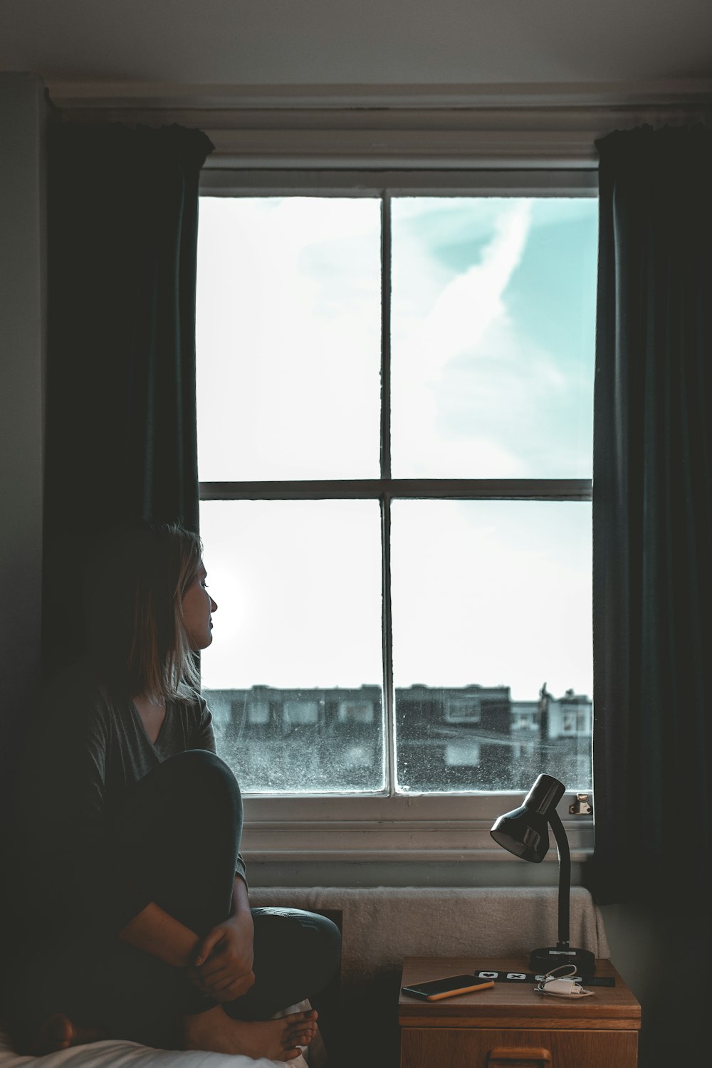 mujer con polainas negras sentada junto a la ventana
