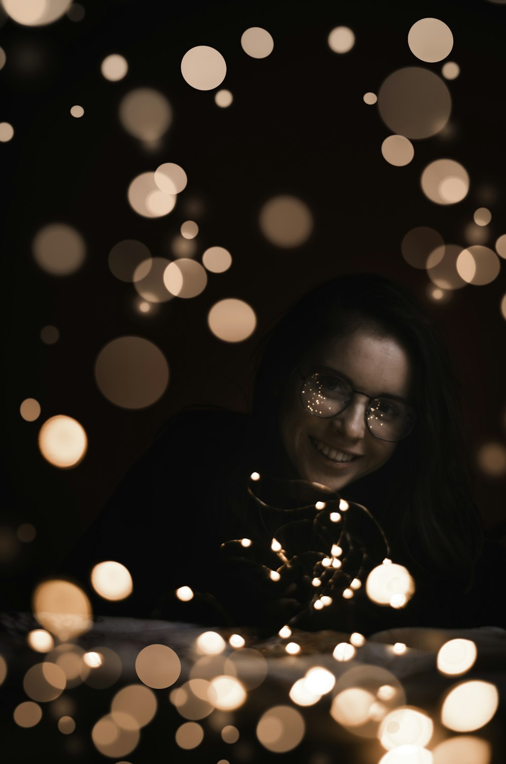 bokeh photography of woman wearing black shirt and black framed eyeglasses