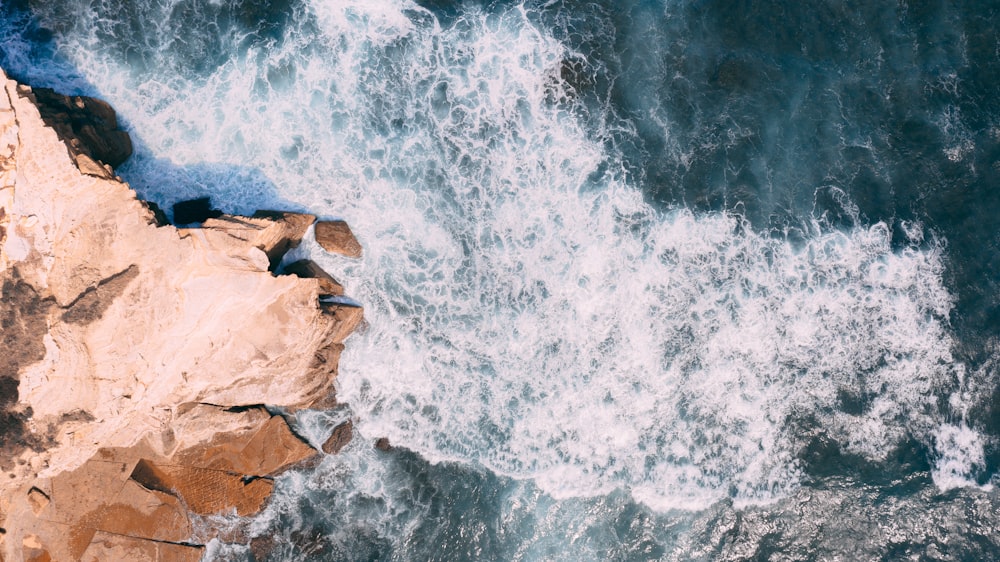 waves crashing on rocks during daytime