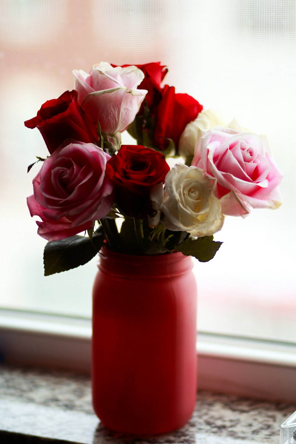 pink, red, and white roses with red mason jar vase