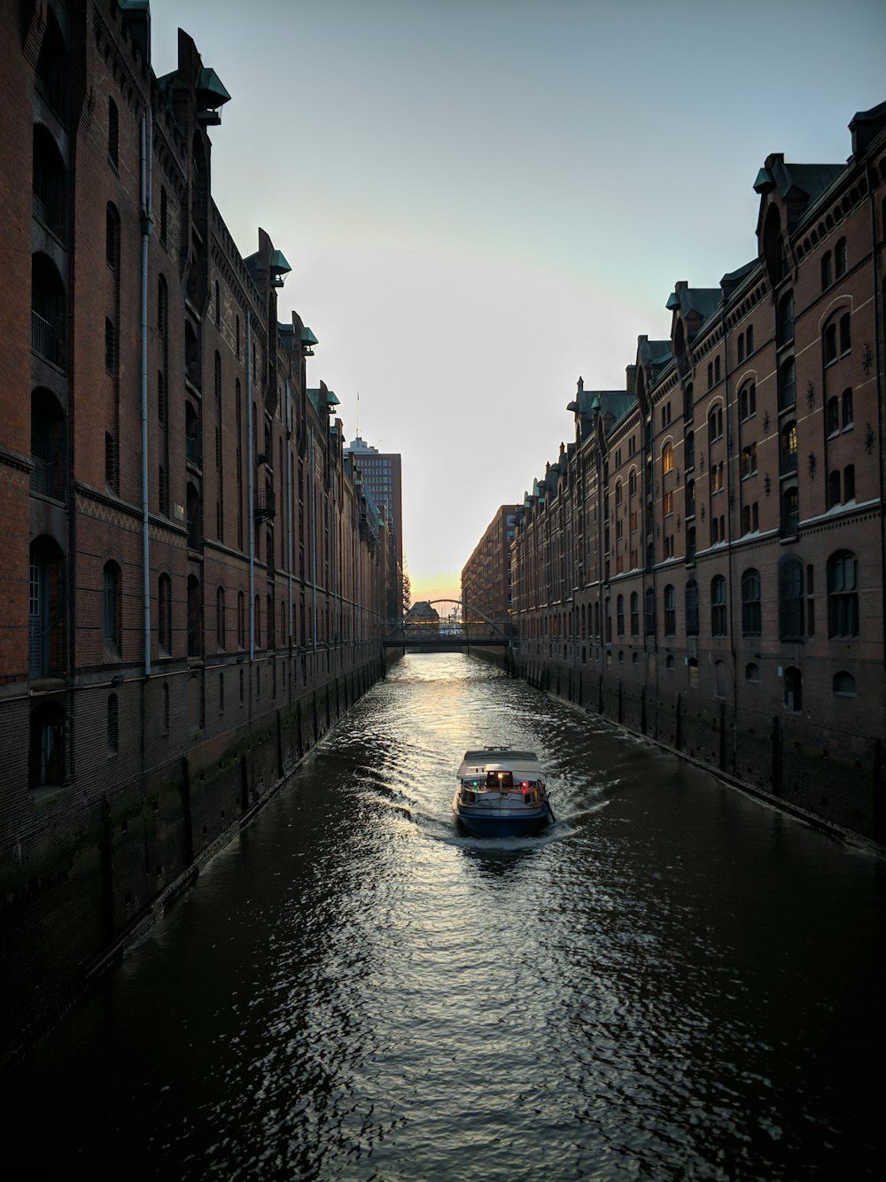 ski boat on canal beside buildings during day